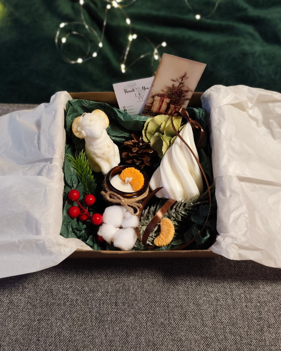 Sveču komplekts Ziemas Meža Siltums atvērtā kastītē ar zaļu iesaiņojumu, kokvilnas un ziemīgiem dekoriem