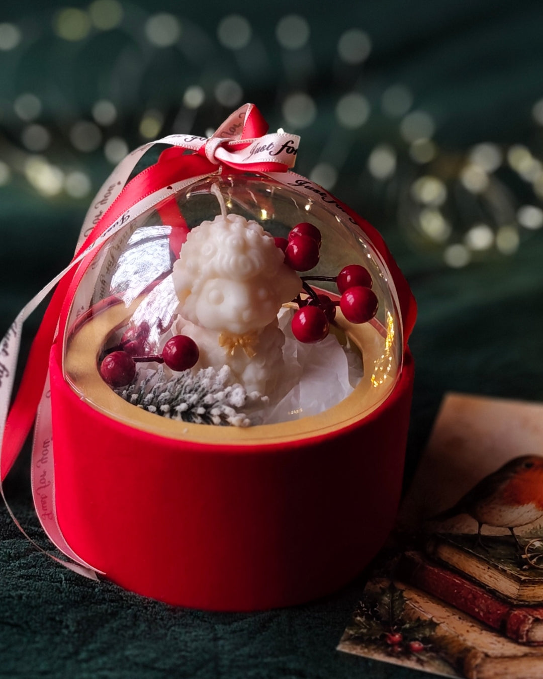 Balta figūrsvece Ziemas Brīnums Kupolā sarkanā kārbiņā zem caurspīdīga kupola ar ogu dekoriem un lentēm