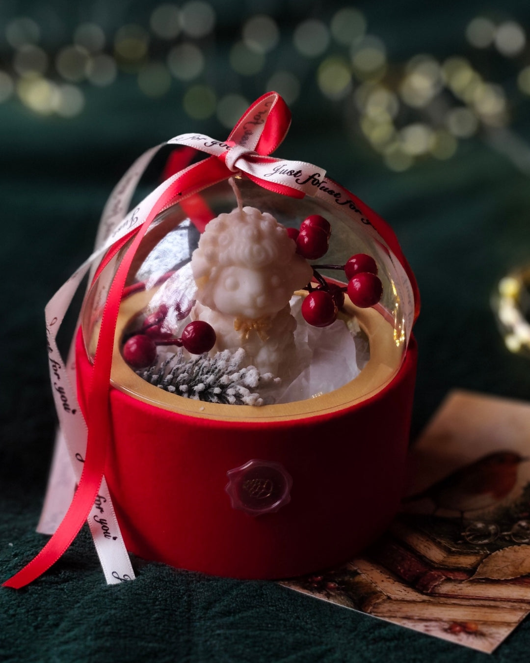 Ziemas Brīnums Kupolā sveces dāvanu noformējums ar sarkanu pamatni, zeltainu apmali un gaišu lenti